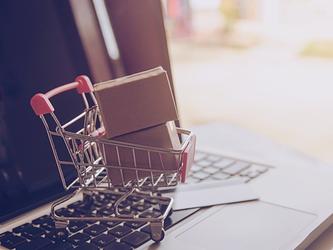 small shopping trolley with packages, on top of laptop keyboard